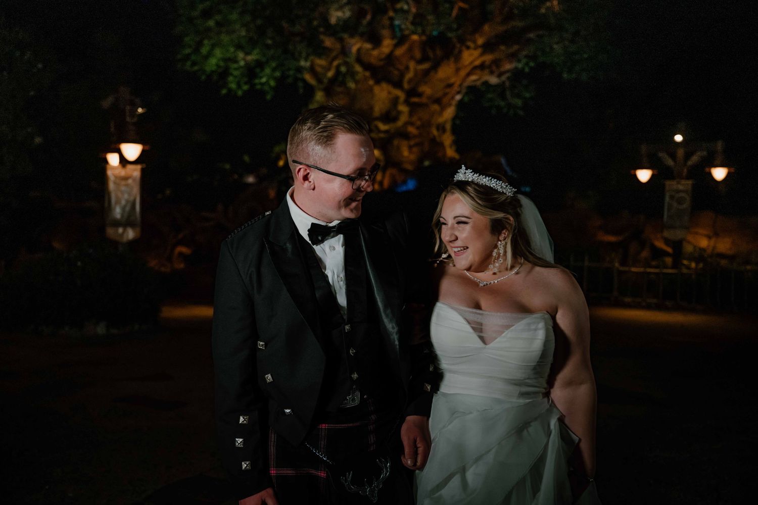 Bride and groom share a joyful moment together outdoors at night during Disney wedding.