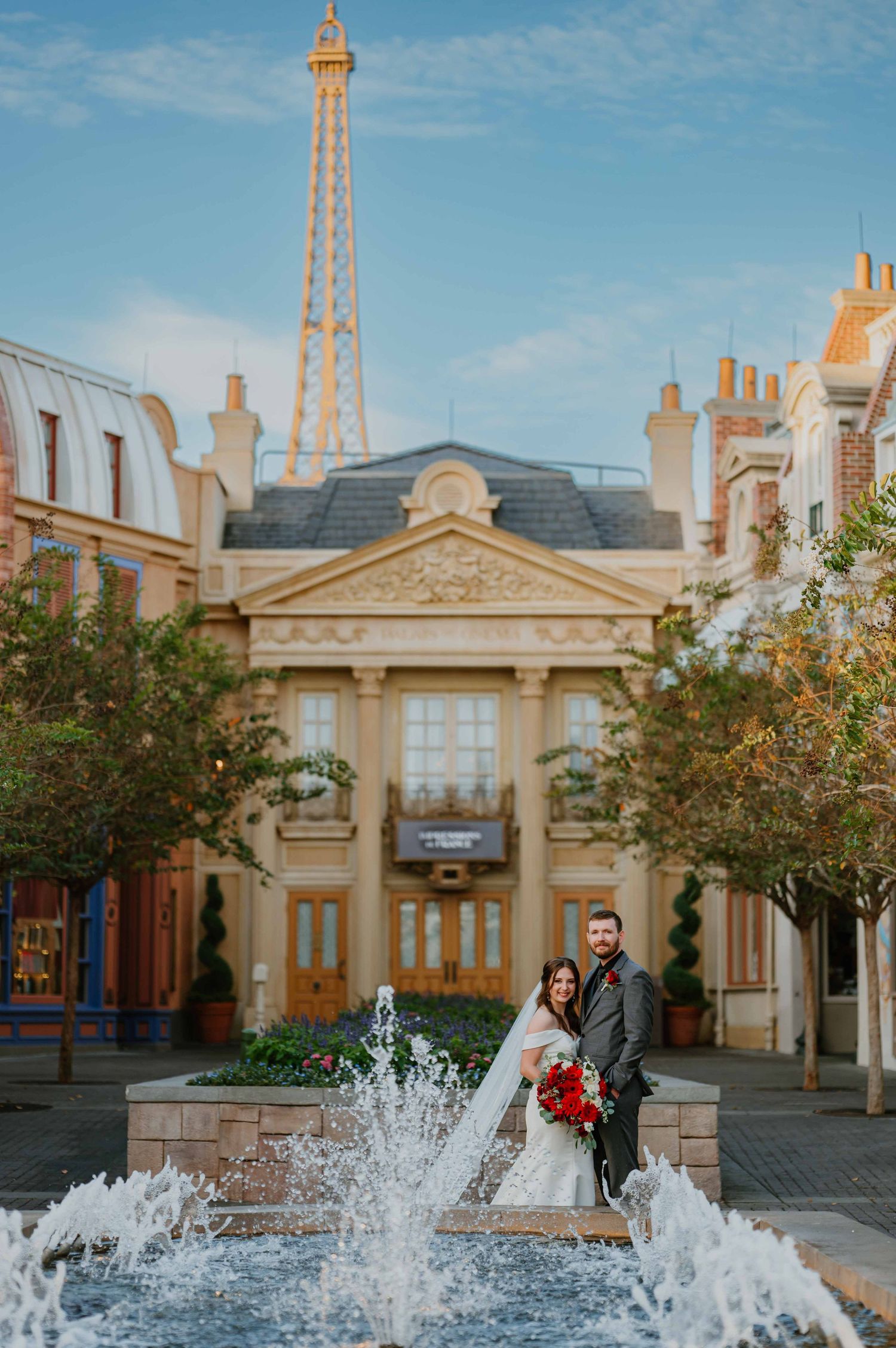 Wedding couple poses by a fountain with the Eiffel Tower replica at Epcot France pavilion.