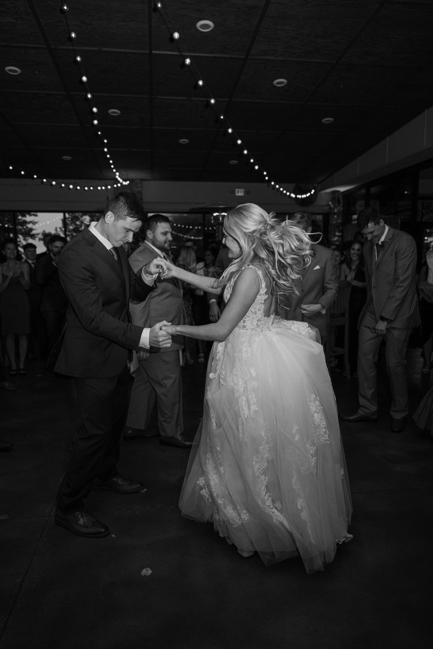 Black and white photo of bride and groom dancing at wedding reception.