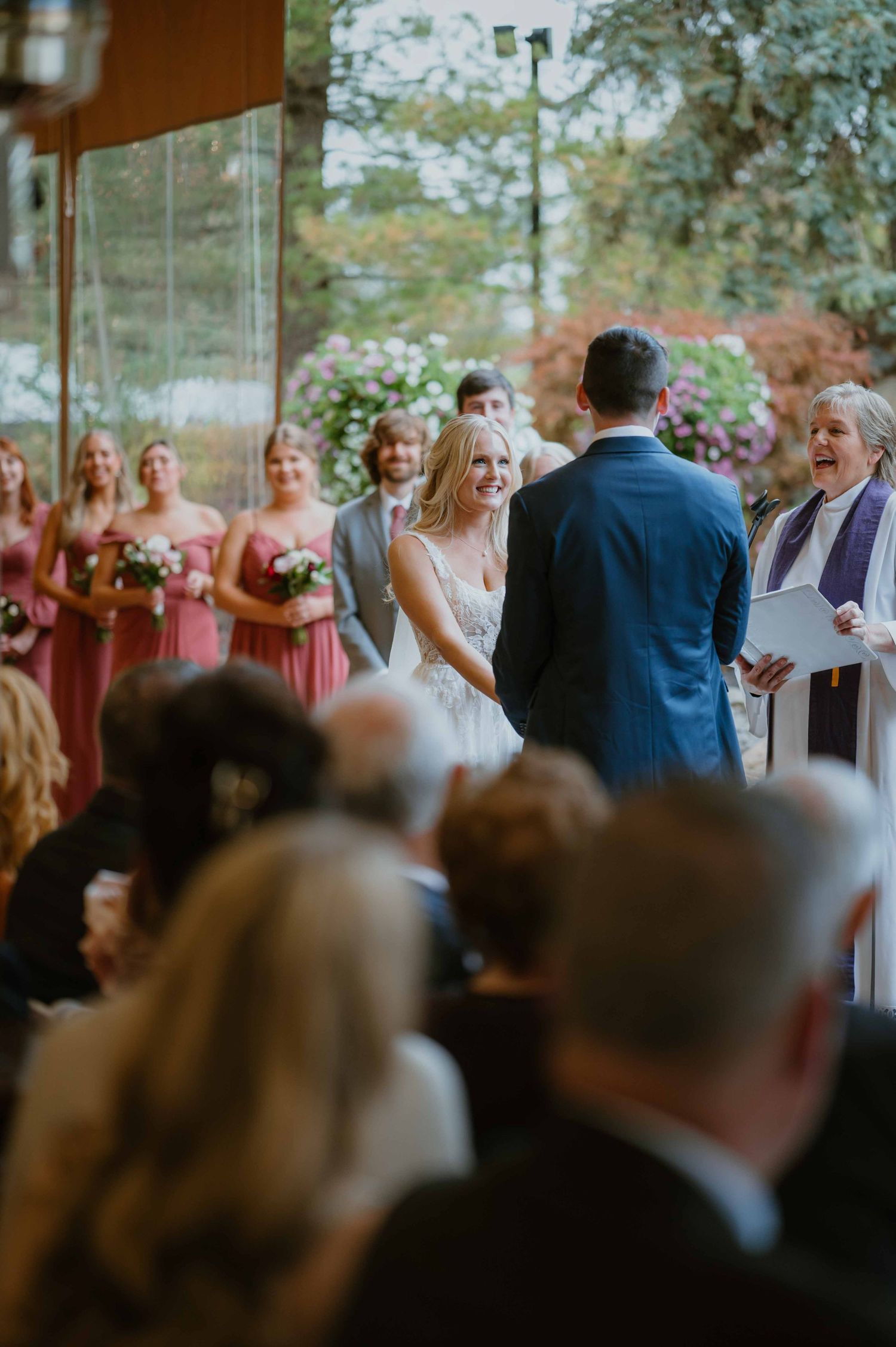Bride and groom exchanging vows at outdoor wedding ceremony with pink bridesmaid dresses.