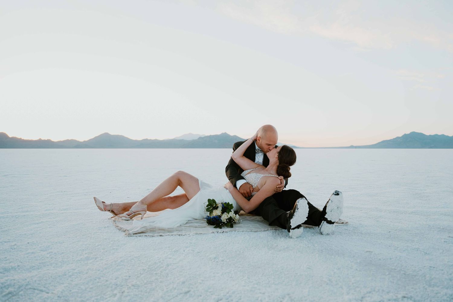 Wedding couple shares a passionate kiss while seated on the expansive Bonneville Salt Flats.
