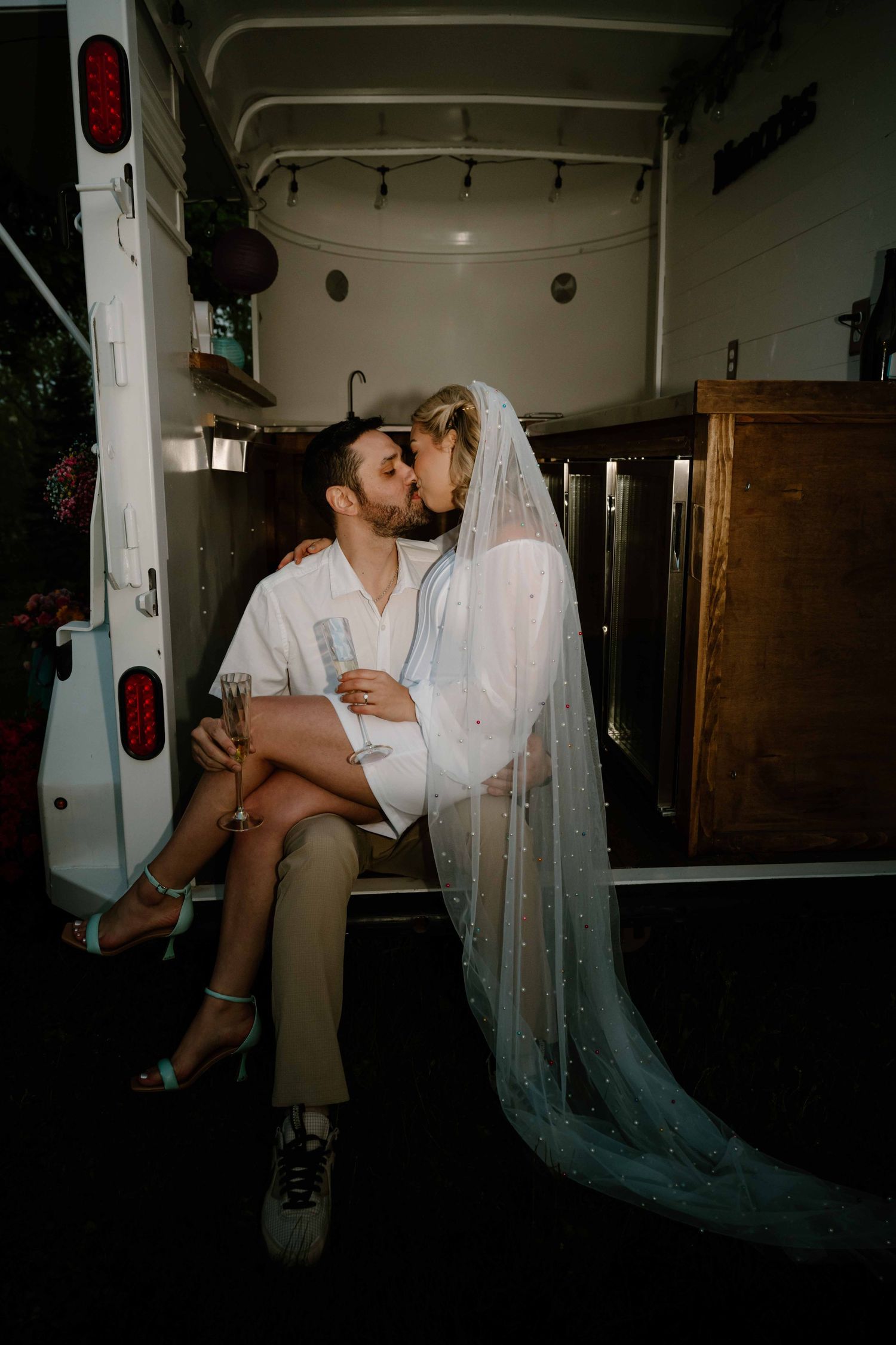 Bride and groom share a romantic kiss inside a vintage van on their wedding day.
