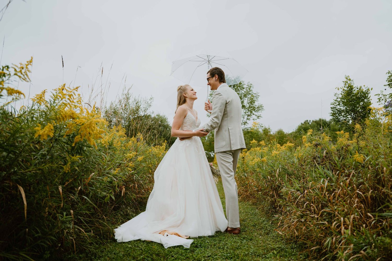 Bride and groom face each other in a wildflower meadow on their wedding day.
