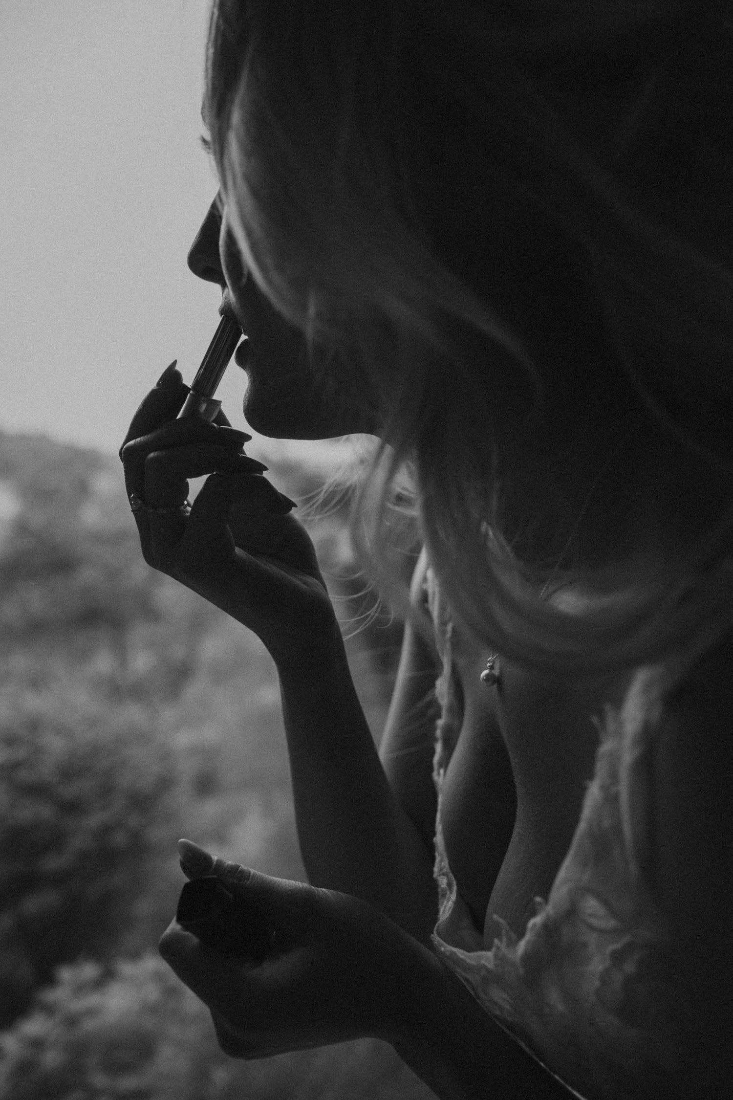 Black and white close-up profile of a blonde bride applying lipstick before her wedding ceremony.