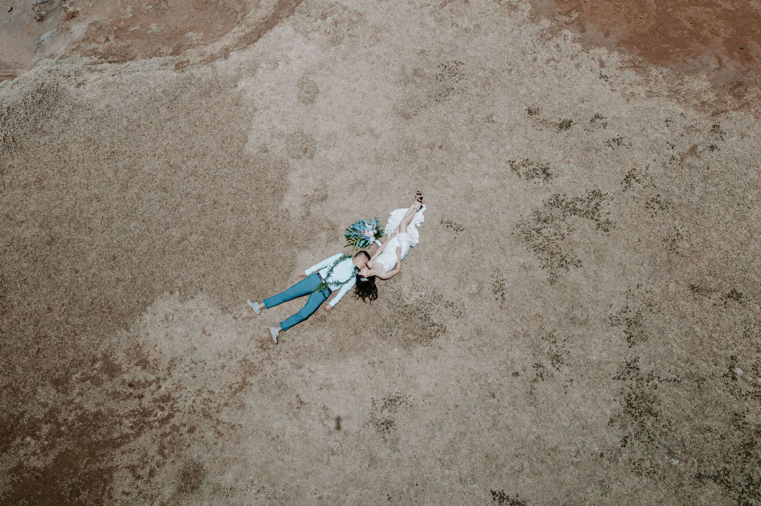Aerial view of a couple lying on sandy ground, captured from above in a romantic drone wedding photo.