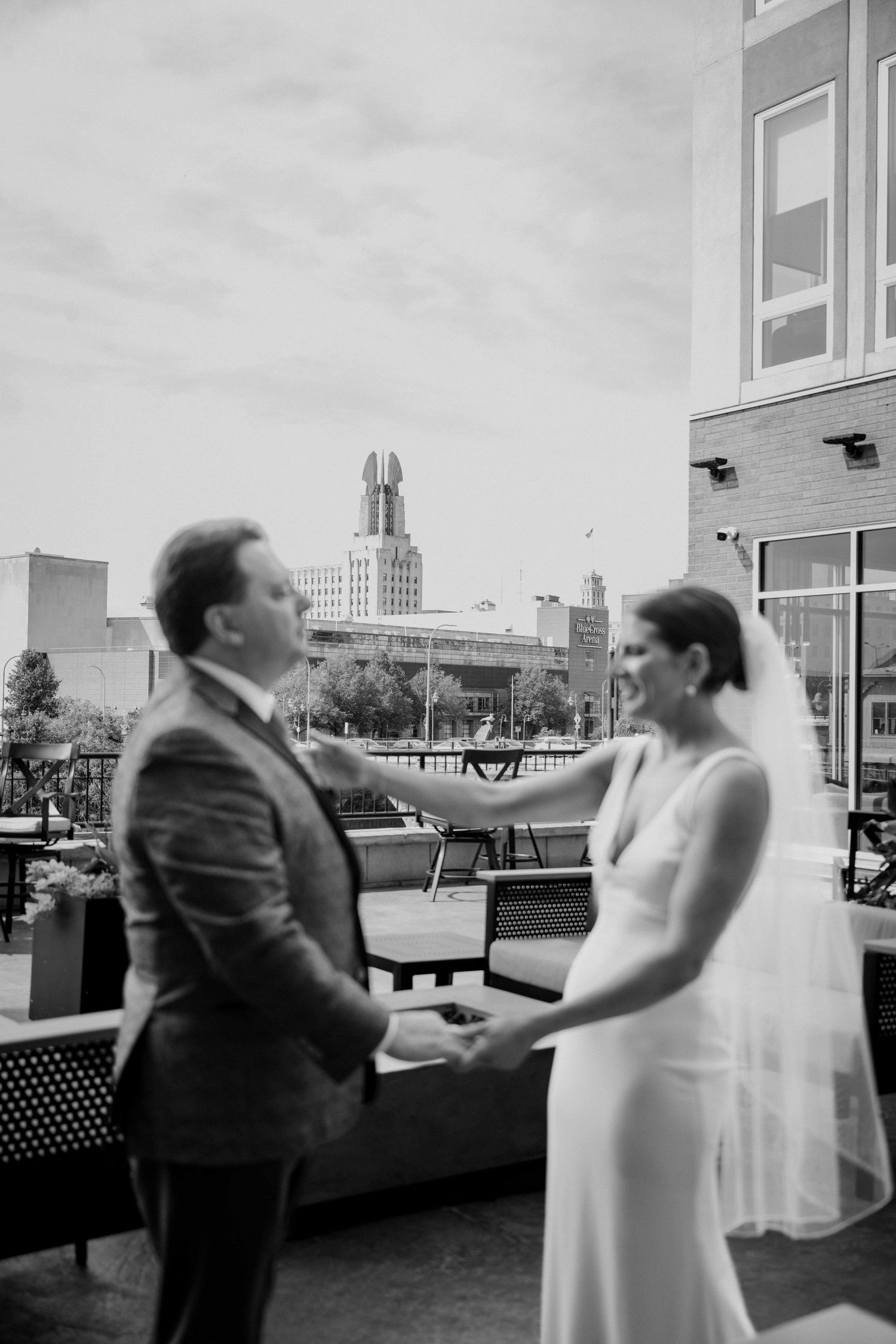 Black and white photo of bride and groom holding hands on rooftop.
