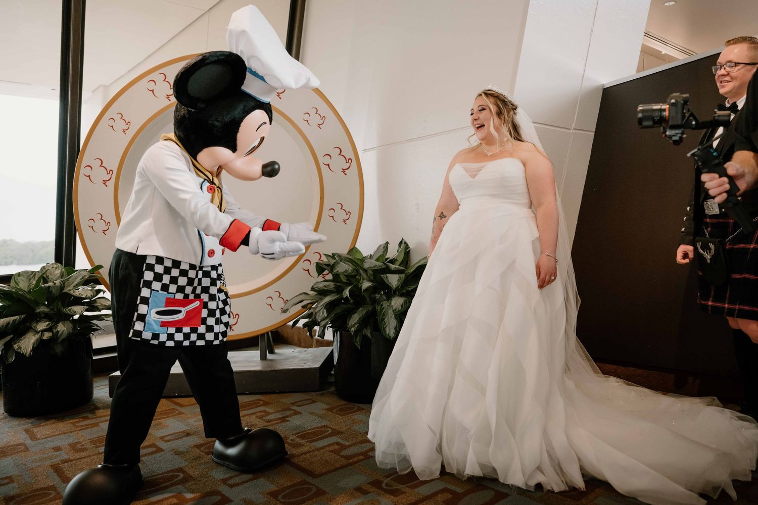 Bride in strapless wedding gown meeting Chef Mickey Mouse character at Disney World wedding celebration.