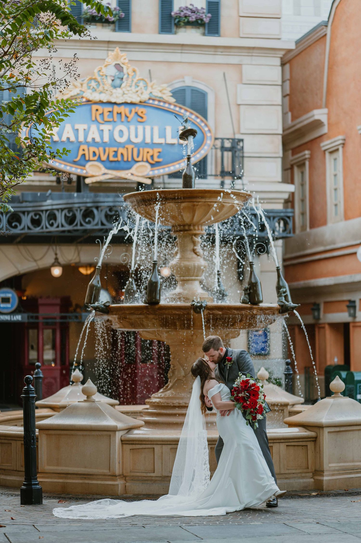 Newlyweds kiss by an ornate fountain near Remy's Ratatouille Adventure at Disney's Epcot park.