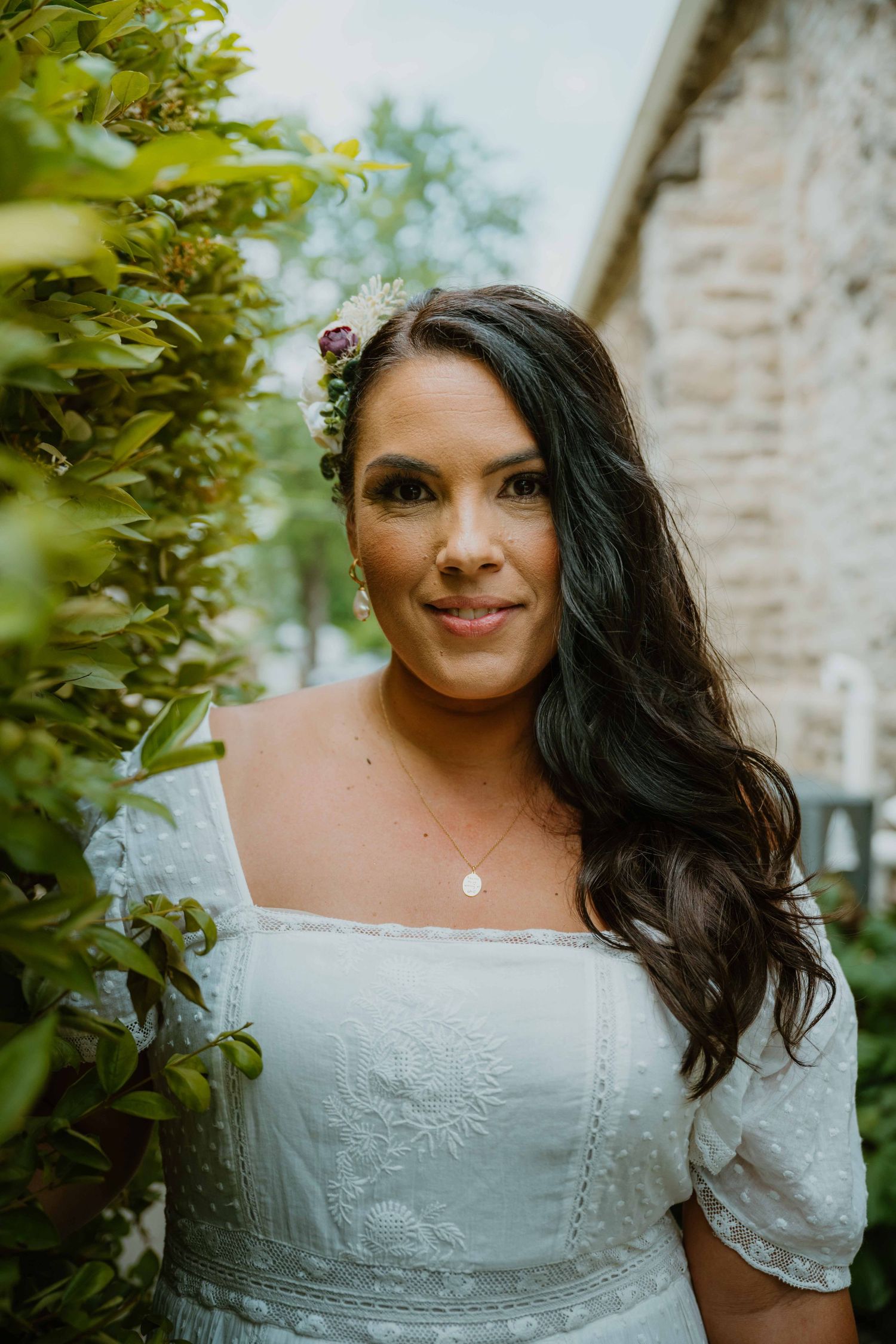 Close-up portrait of a dark-haired bride with floral hair accessories in white dress.