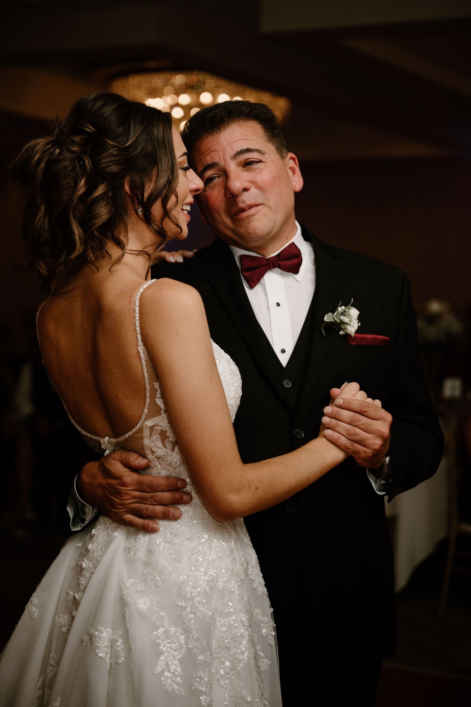 Emotional father-daughter dance at wedding reception, sharing a tender moment in formal attire.