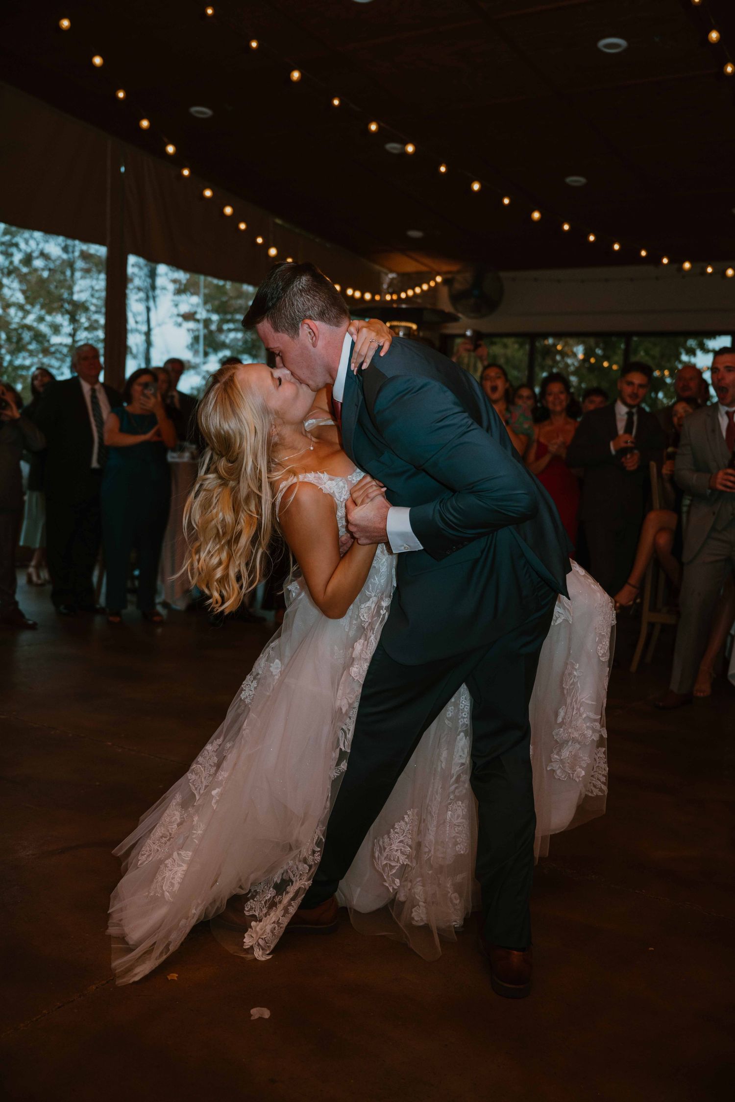 Bride and groom sharing a passionate dip kiss on the dance floor during their first dance.