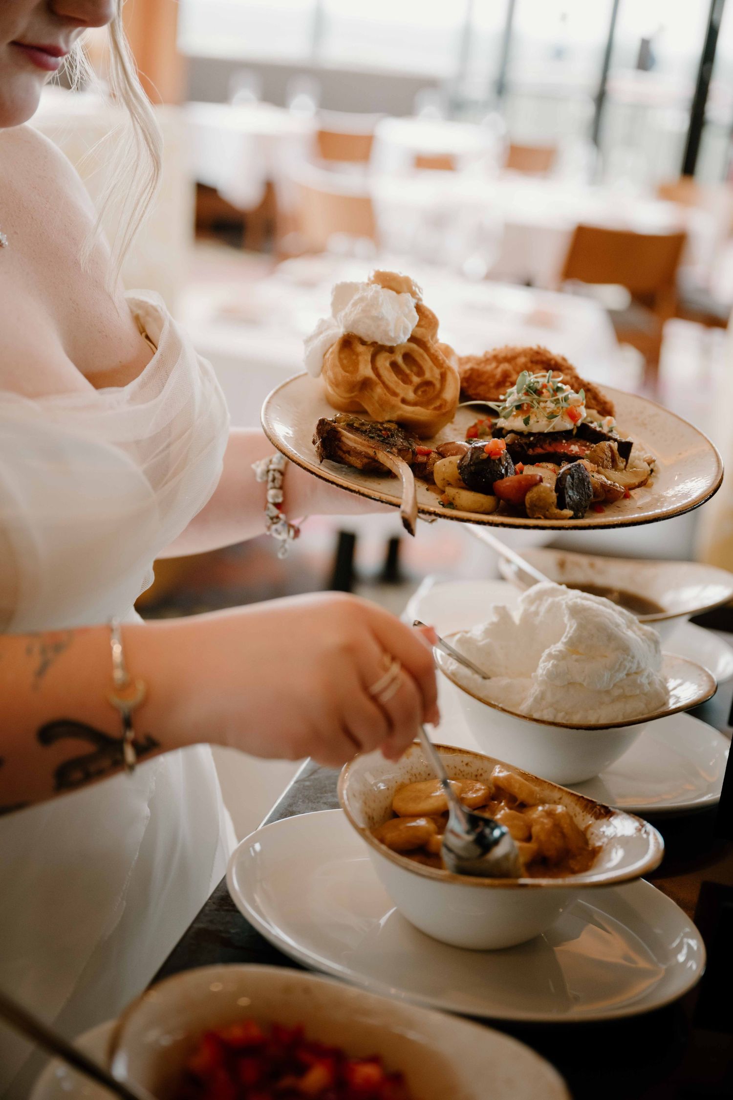 Bride in white dress serving dessert plates with whipped cream and fruit at wedding reception.