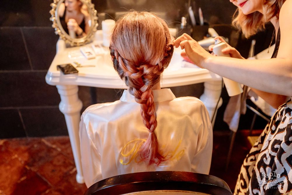 Close-up of braided hairstyle being styled during wedding preparation.
