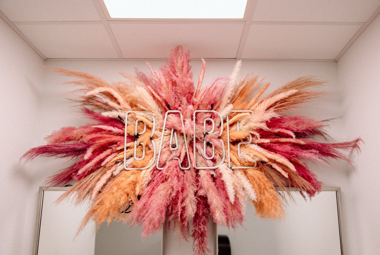 Modern pink and orange feathered light fixture creating a dramatic ceiling installation.