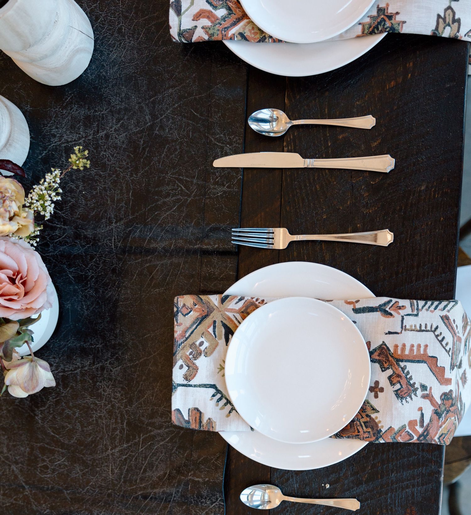 Elegant table setting with white plates and silverware on a dark surface.