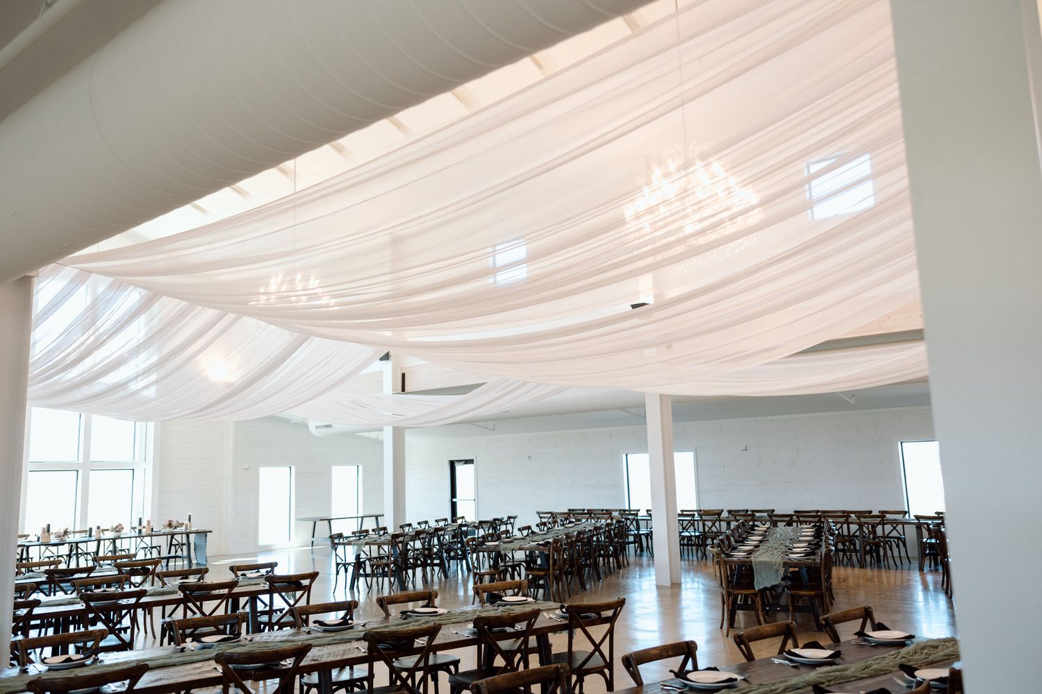 Large white event space with draped fabric ceiling and rows of dark chairs.