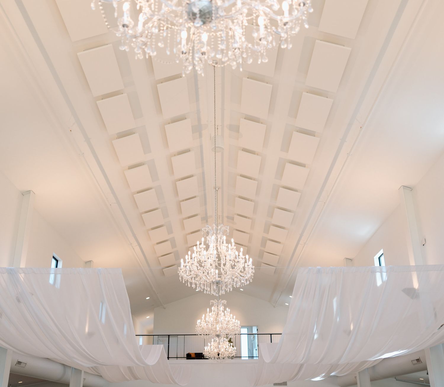 Elegant white event space with crystal chandeliers and coffered ceiling details.