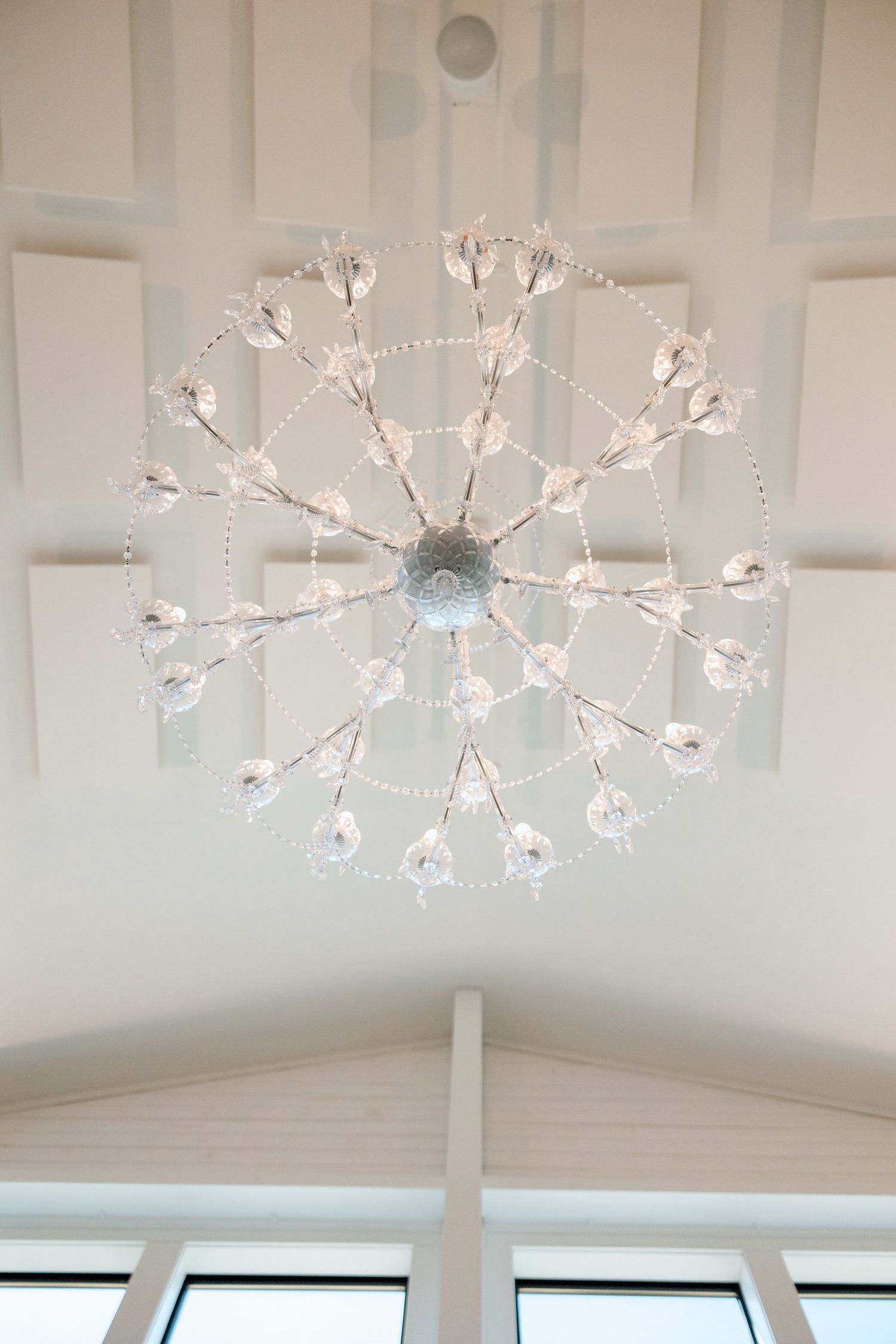 Elegant crystal chandelier lighting fixtures mounted on a white geometric ceiling.