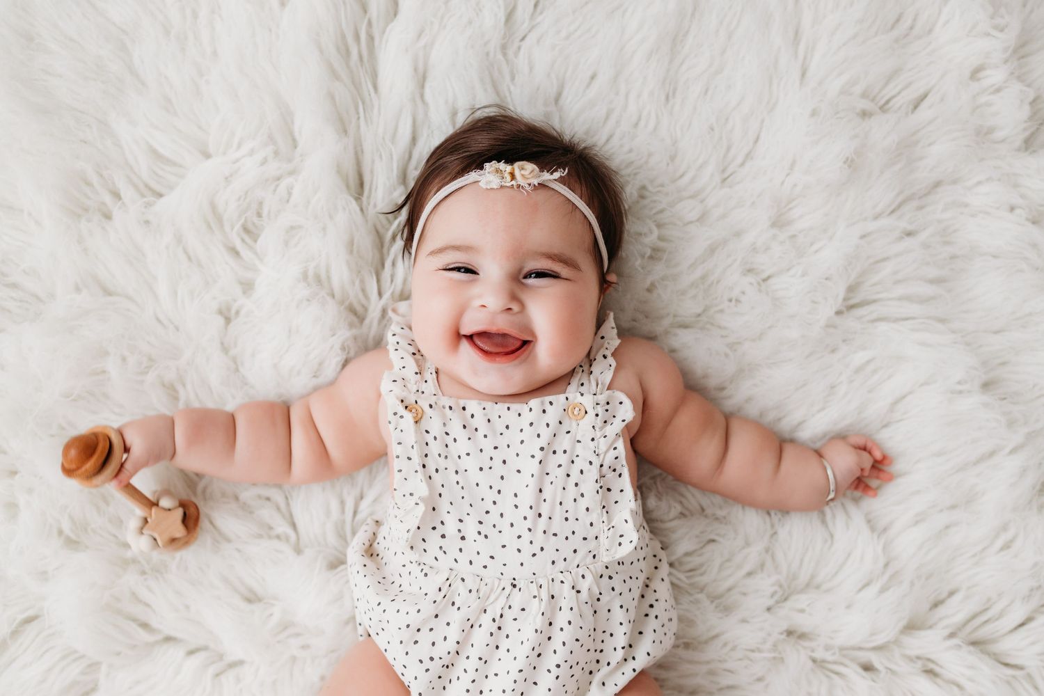 7 month old baby laying down looking up at camera laughing. Photo captured by Santa Fe baby photographer