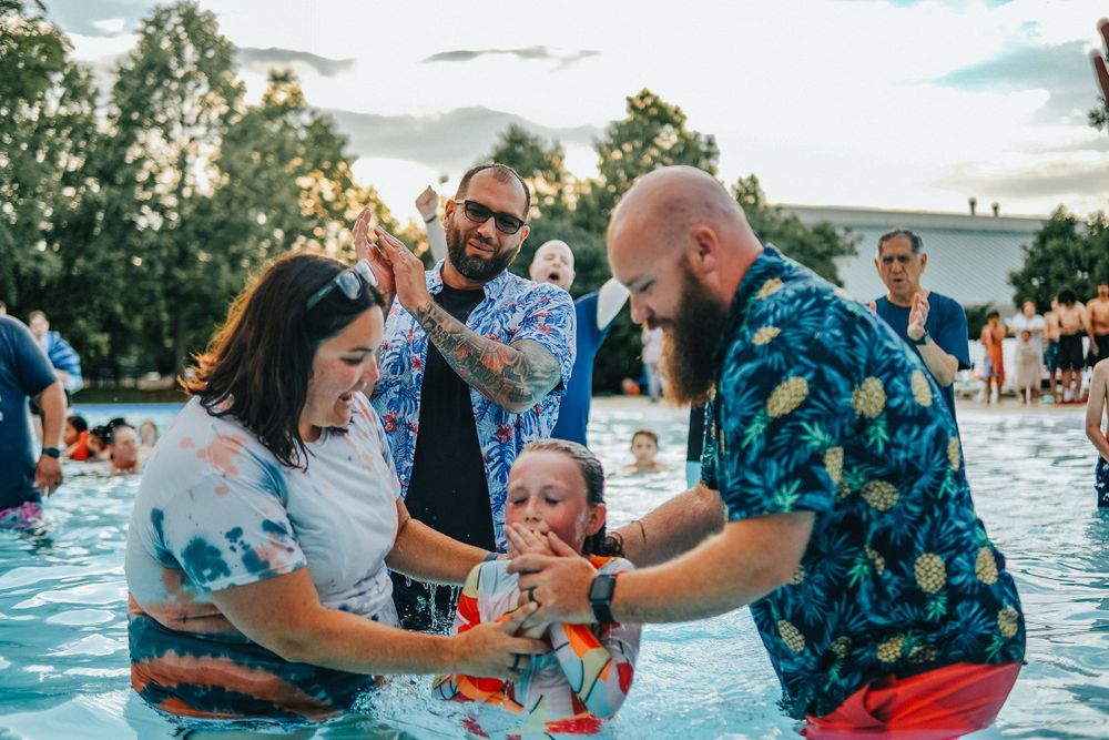 People enjoying a fun moment together in a swimming pool on a sunny day.