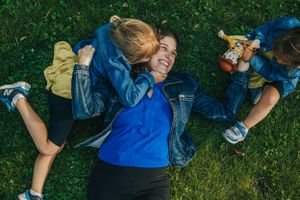 People playing and having fun while lying on green grass outdoors.