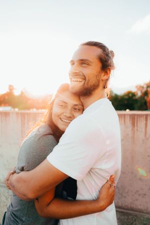 A loving couple shares a warm embrace during golden hour sunset.