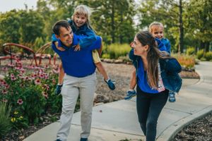 A family wearing coordinating blue outfits walks together on a garden path.