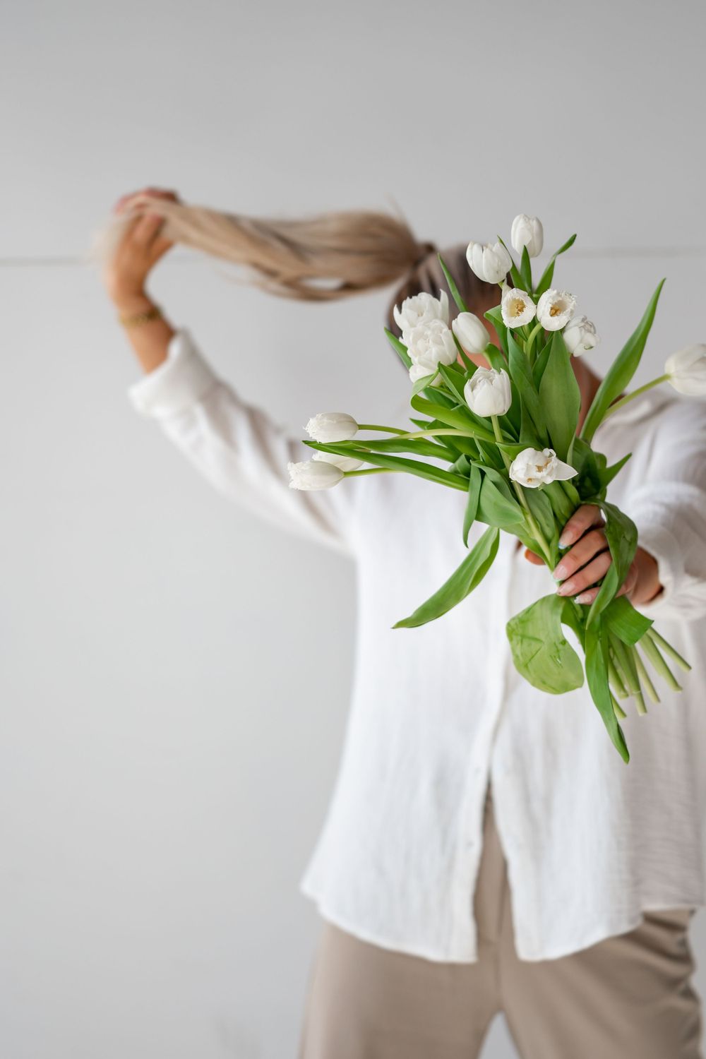 Creative shot of hands holding white tulips while playing with long hair.