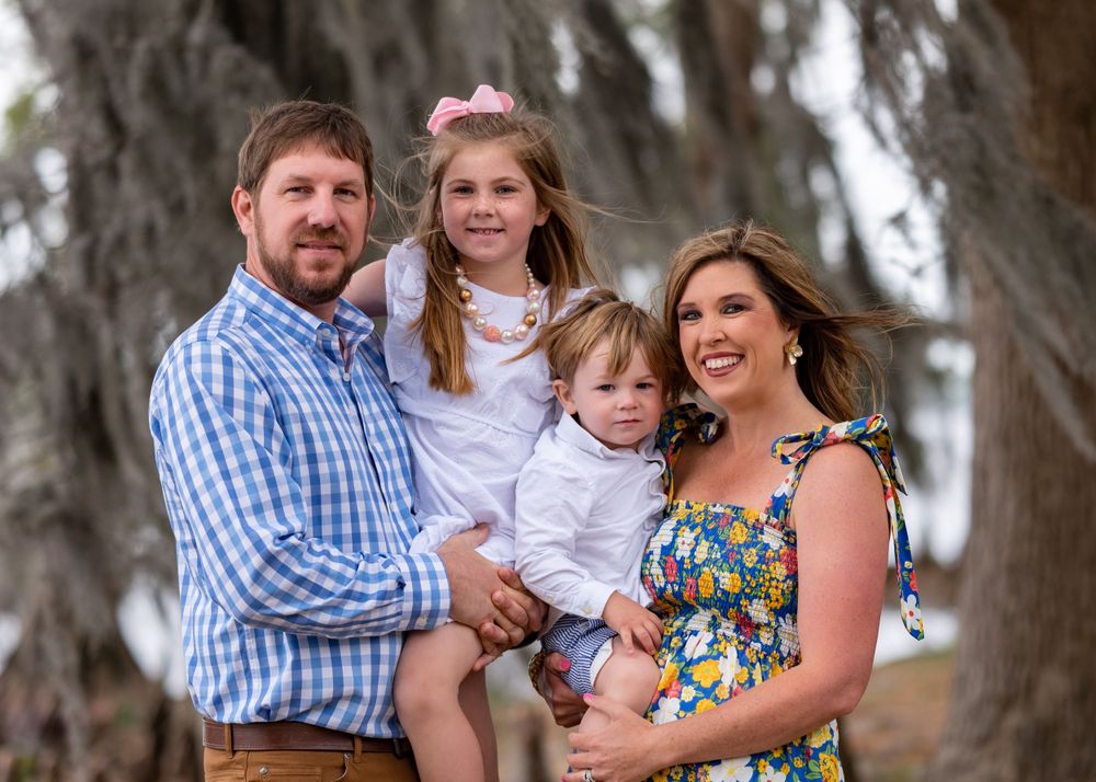 Outdoor family portrait captured against scenic moss-draped trees.