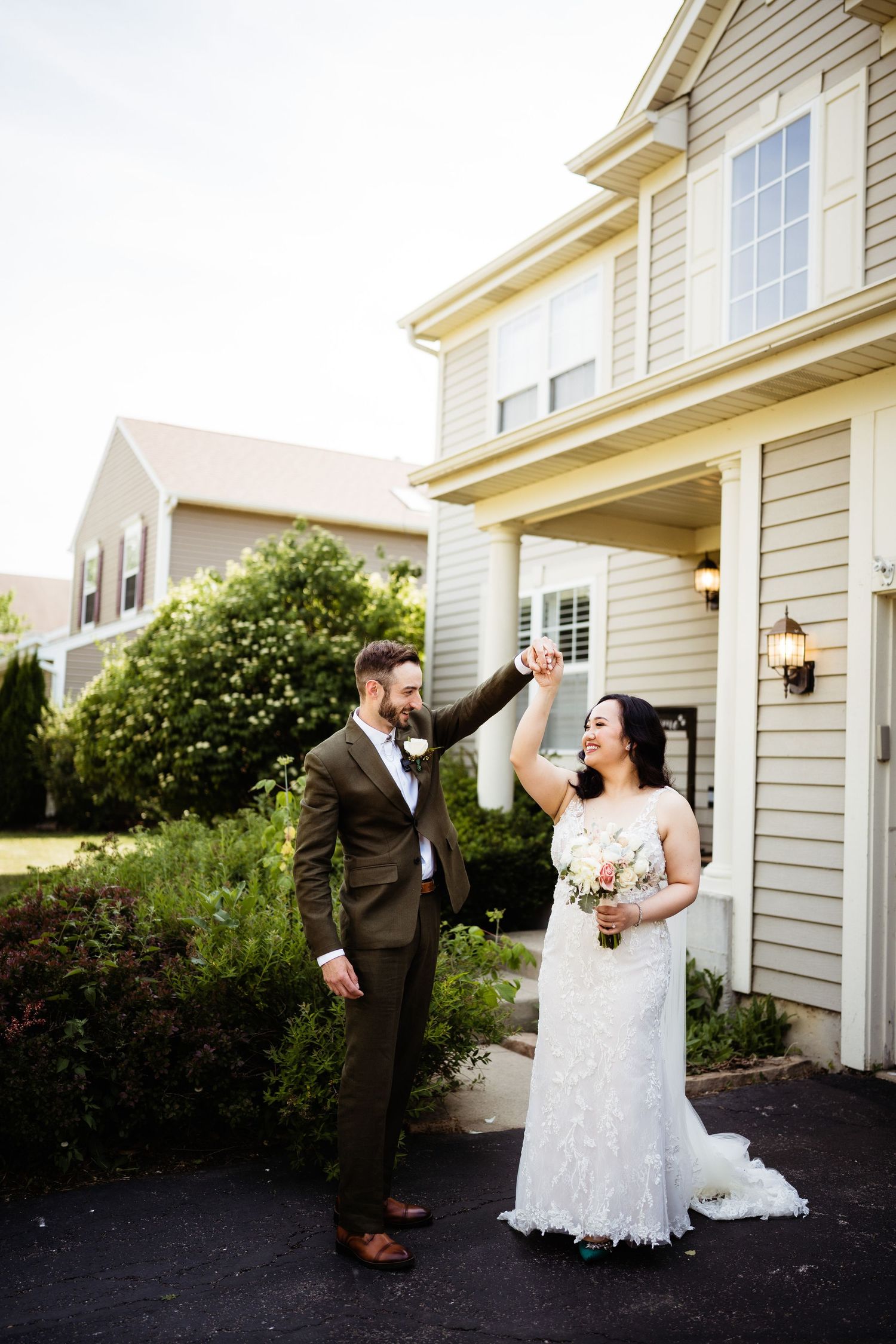 Newlyweds share a joyful moment outside their home during wedding photoshoot.