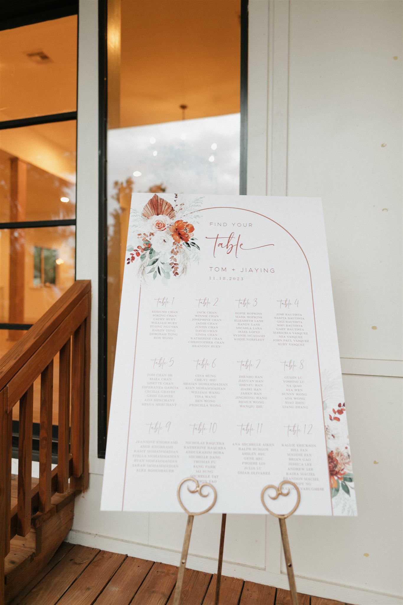 Elegant floral wedding seating chart displayed on wooden easels at venue entrance.