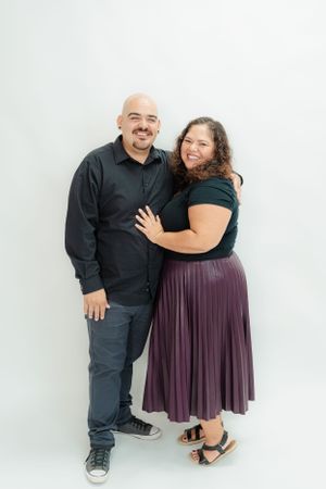 Smiling couple posing together affectionately during a white background studio portrait session.