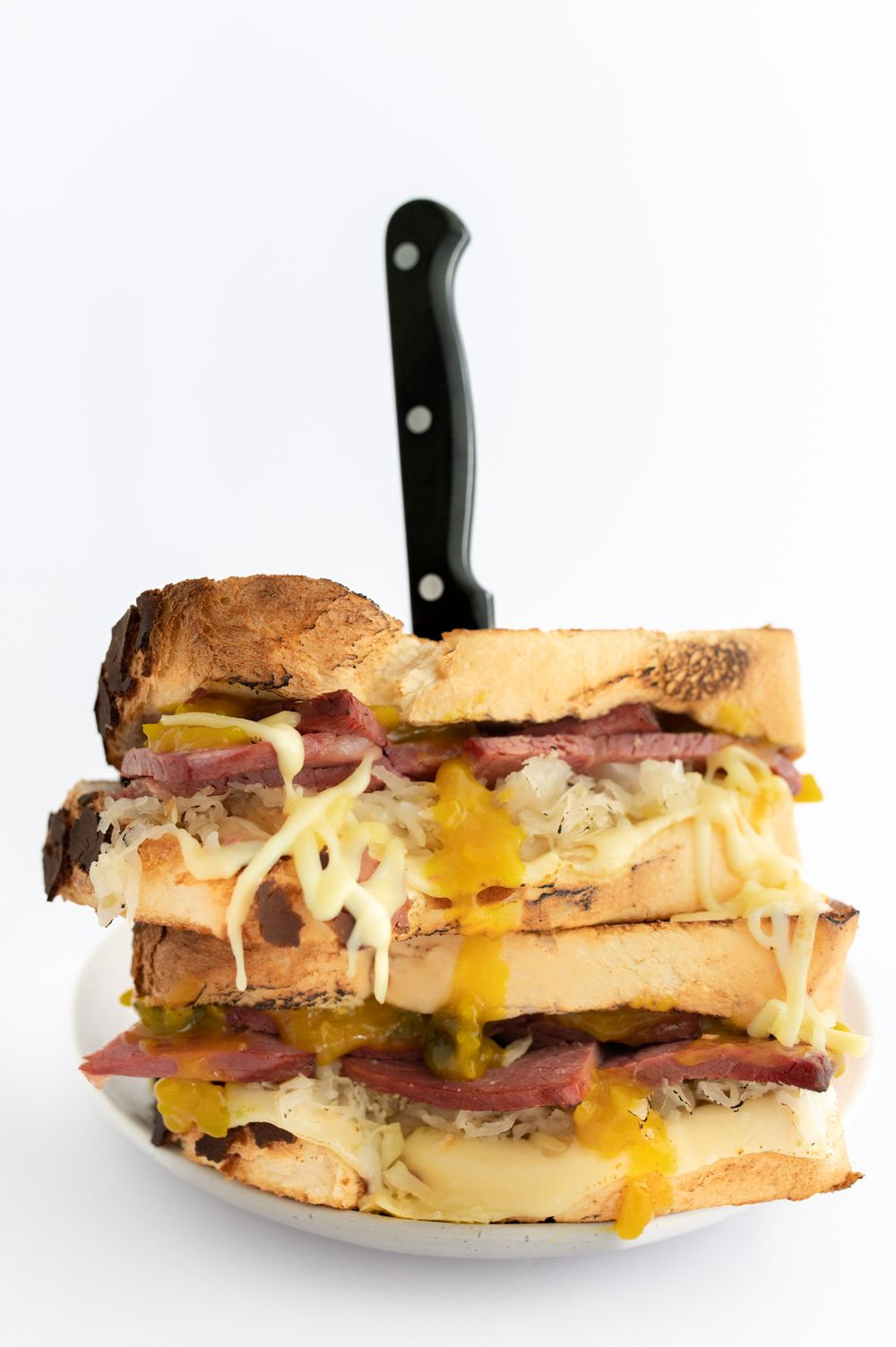 Delicious chunky corn beef sandwich with knife in it.