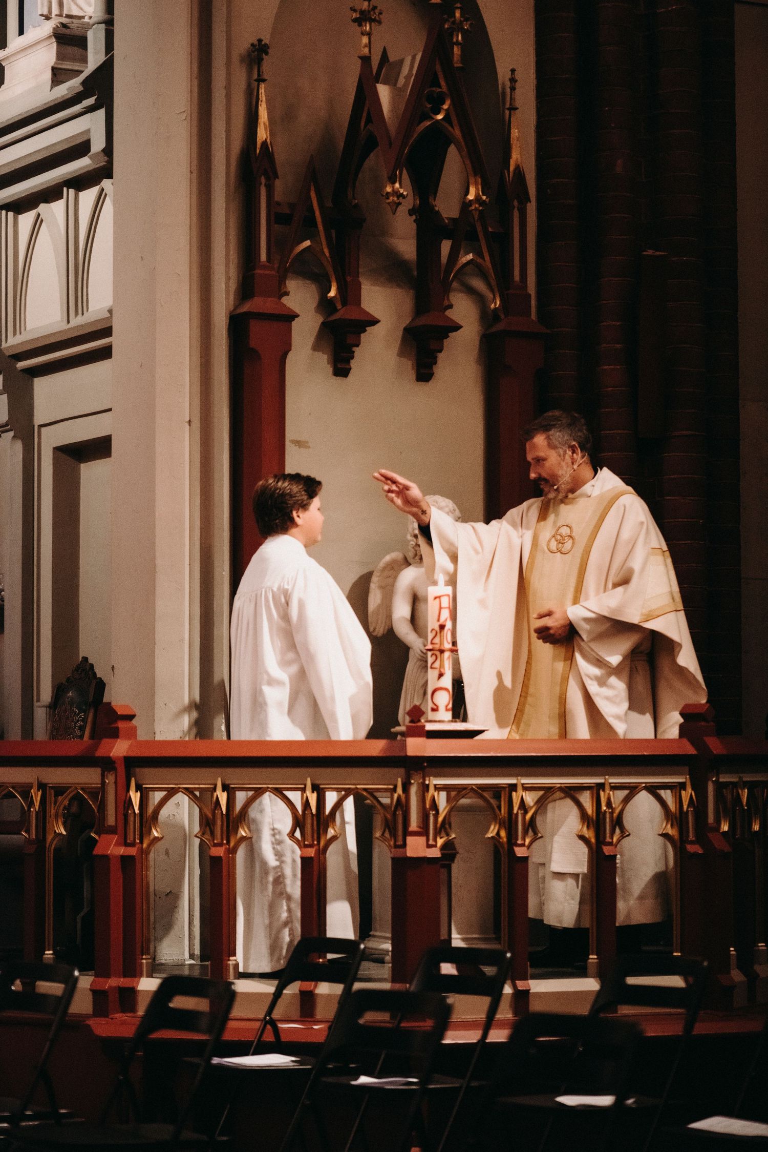 Religious ceremony taking place at an ornate church altar with Gothic architectural details.