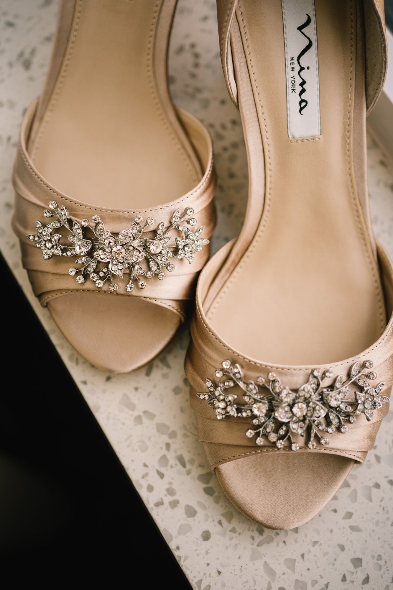 Champagne colored bridal shoes with crystal embellishments and peep-toe design.
