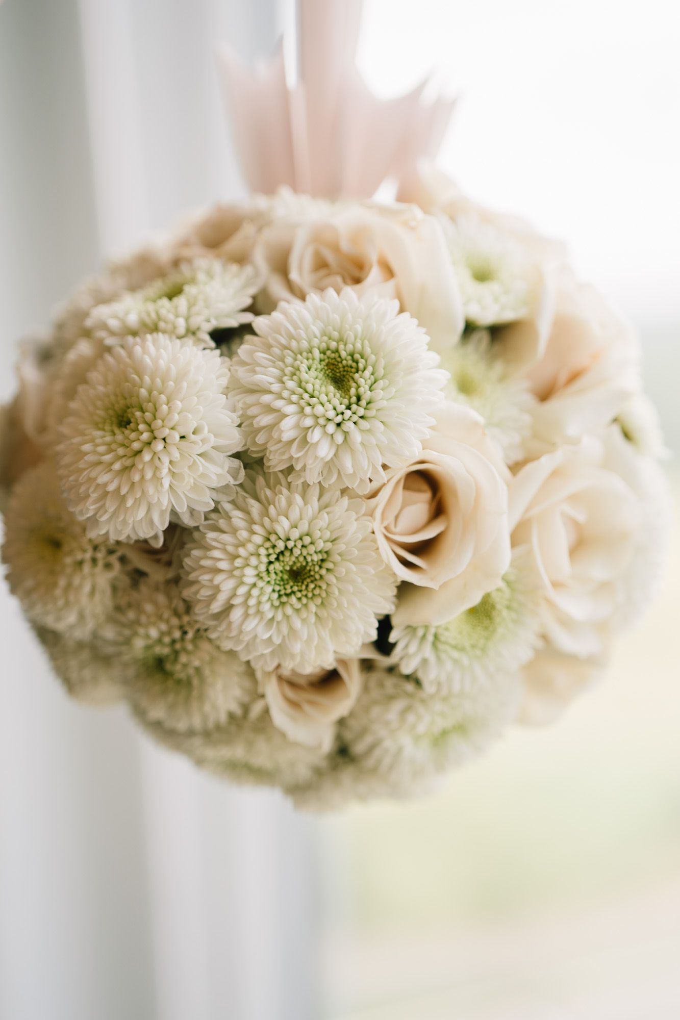 Elegant wedding bouquet featuring white chrysanthemums and cream roses in a soft, romantic arrangement.