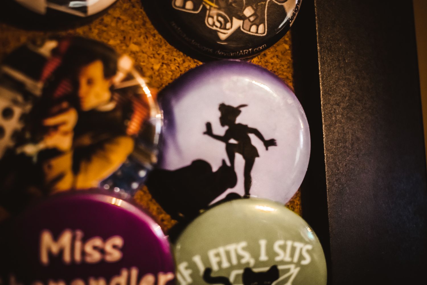 Close-up of decorative pin showing silhouette of witch figure against purple background.