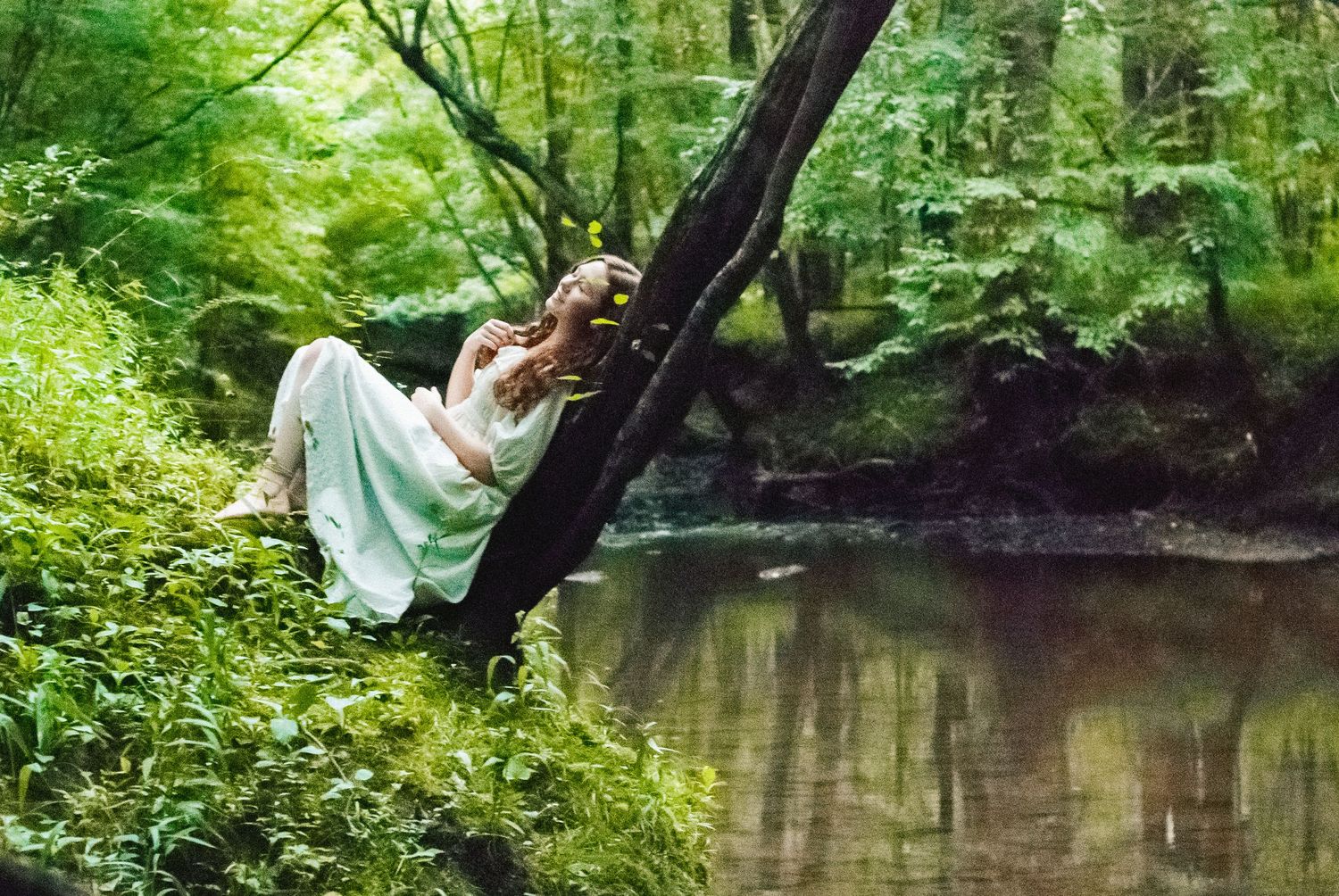 Woman laying against a tree over a creek in Charlotte, North Carolina