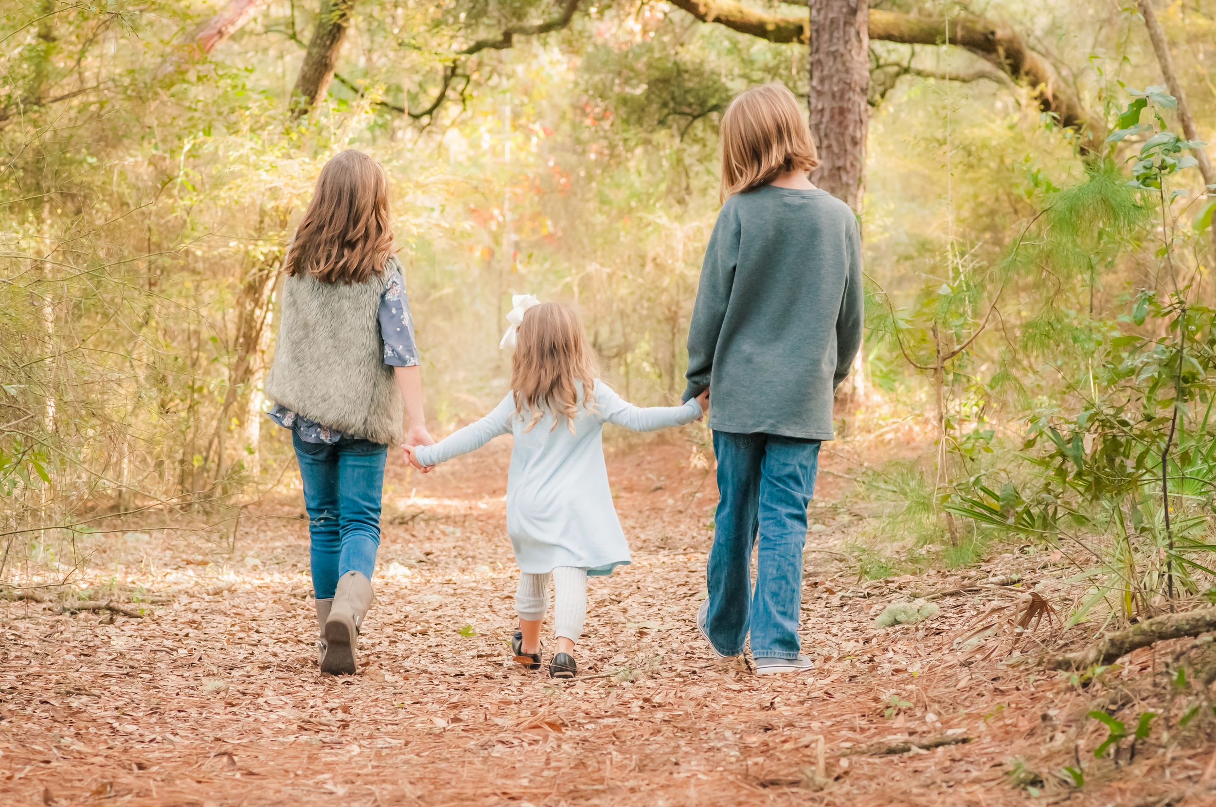 kids walking down path holding hands during family photo session in Panama City Florida