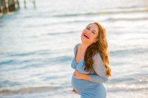 mother to be laughing during maternity beach photoshoot at sunset on Panama City Beach Florida