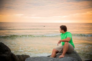 senior looking at the sunset during his portrait session at sunset on Panama City Beach Florida