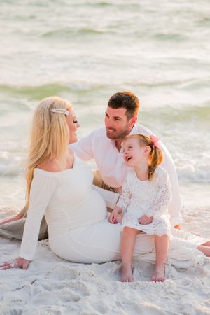 family of 3 sitting on the beach during family beach portrait session at sunset on Panama City Beach Florida
