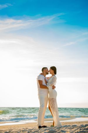 couple kissing during family beach portrait session at sunset with on Panama City Beach Florida