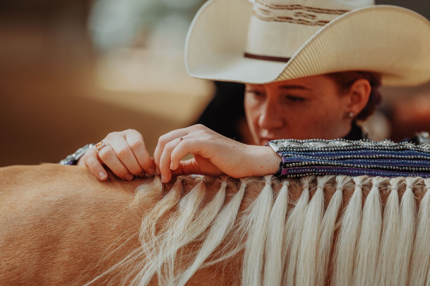 Close-up of hands braiding a horse's mane with precision and care.
