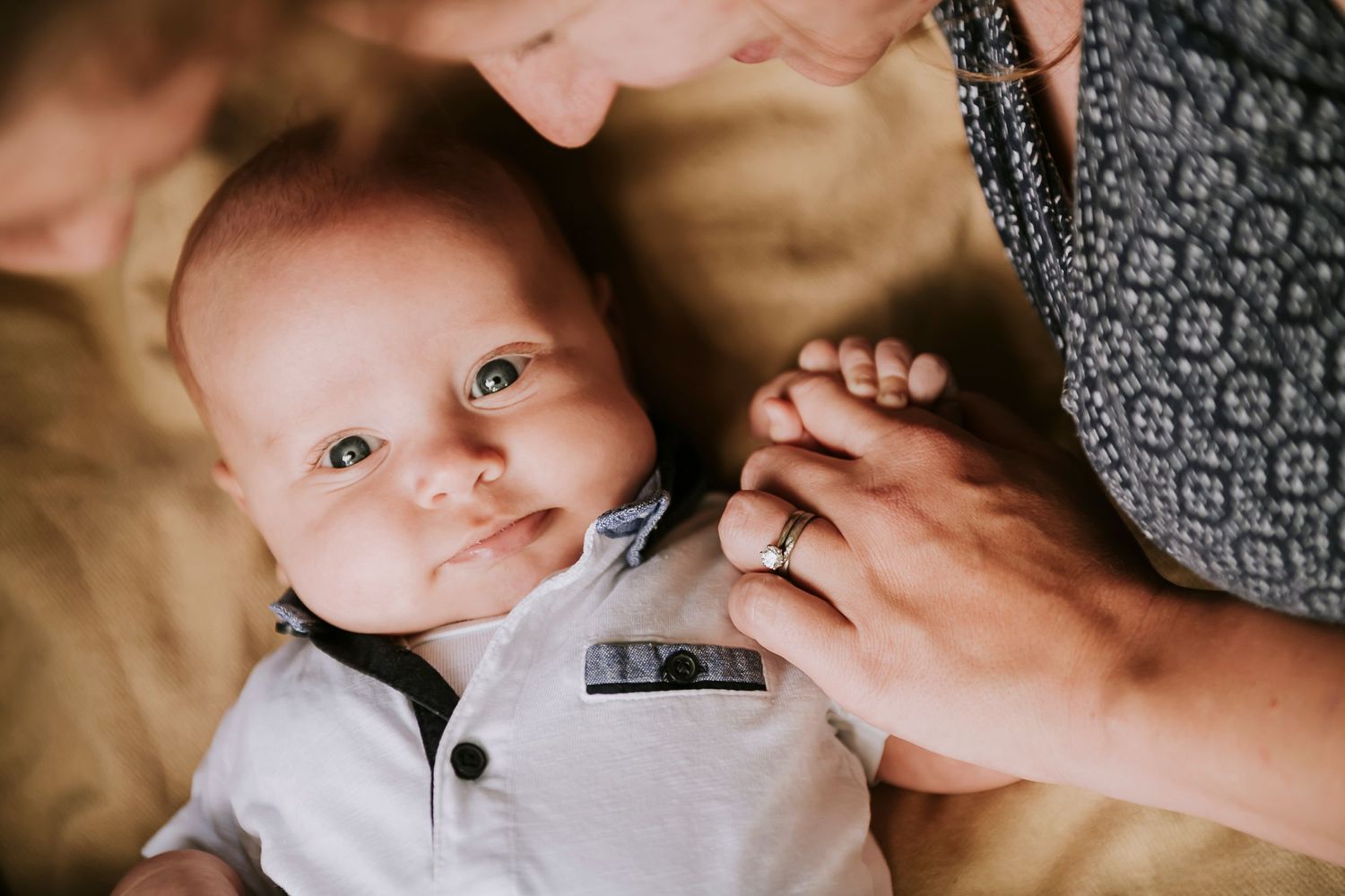 Close up view of a tiny baby in white clothing being held with tender care.