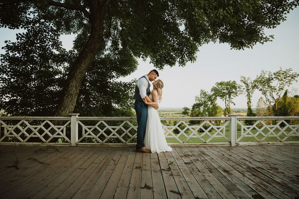 Romantic sunset portrait of newlyweds on a wooden deck with lattice railings.