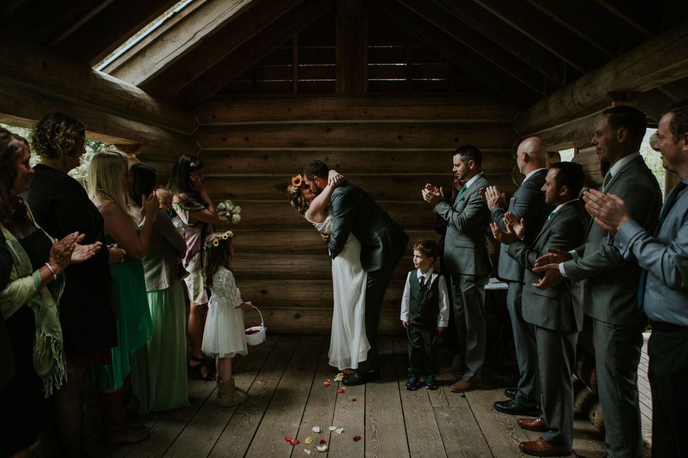 Wedding guests line wooden barn walls holding sparklers during a romantic indoor celebration with rustic ambiance.