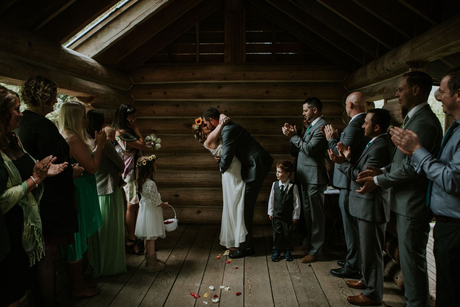 Wedding guests line wooden barn walls holding sparklers during a romantic indoor celebration with rustic ambiance.