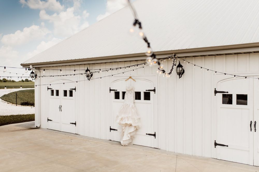 White barn exterior with string lights and three garage doors makes a charming venue setting.