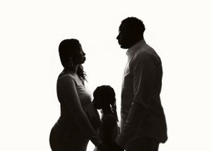 Black and white silhouette portrait of an expectant family.